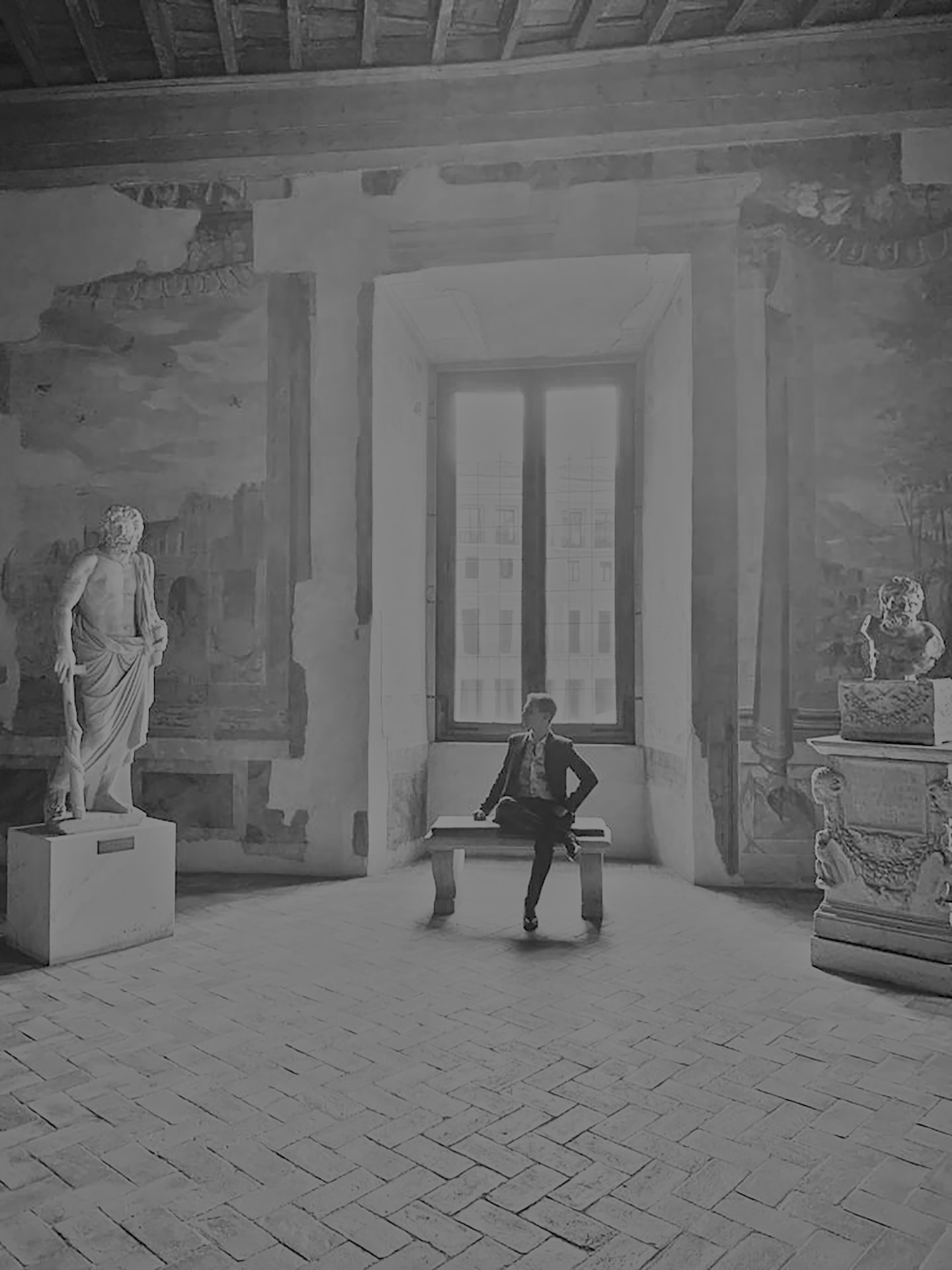Simone Ferrari seated on a bench in a frescoed hall of Palazzo Altemps